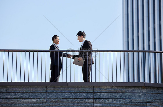 高楼下的都市白领商务洽谈握手图片