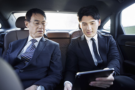 年轻助理坐在轿车里给老板汇报工作图片素材