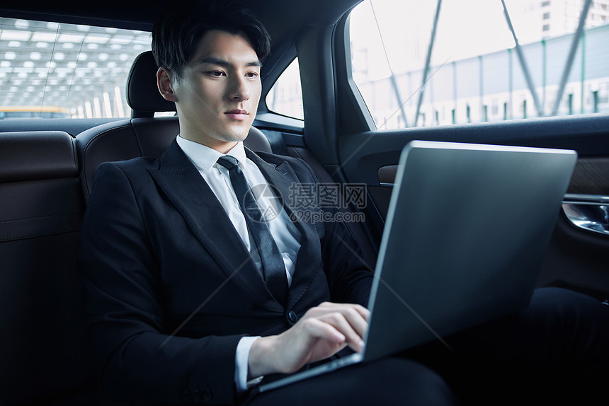 年轻白领坐在轿车里用笔记本电脑办公图片