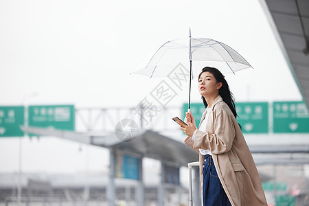 户外撑伞等车的女性图片