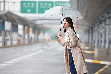 户外撑伞等车的女性高清图片