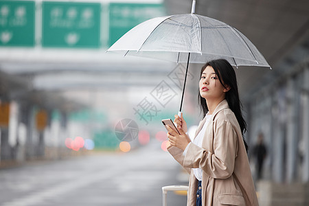 户外撑伞等车的女性图片