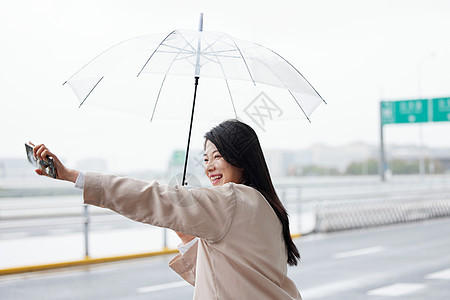 户外撑伞拦车的年轻女性背景图片