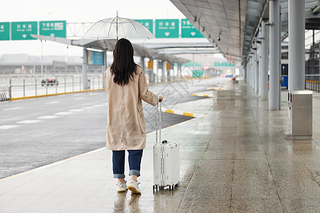 在机场室外撑伞等车的女性背影背景图片