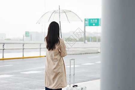 室外撑伞等车的女性背影图片