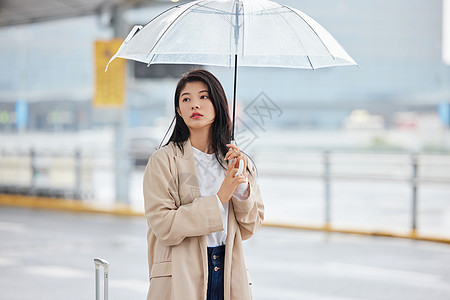 下雨天撑伞等候的女性背景图片