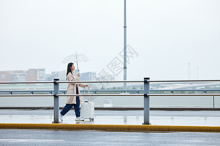 雨天撑伞行走的年轻女性图片