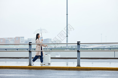 雨天撑伞行走的年轻女性背景图片