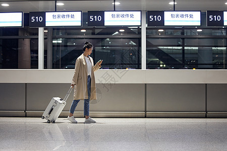 商务女性夜晚机场拉着行李箱行走图片