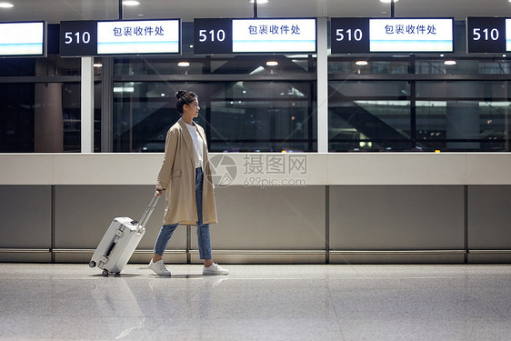 商务女性夜间出行在机场拉着行李箱图片