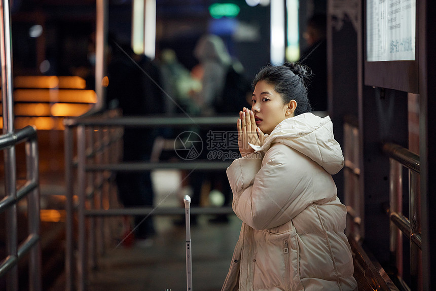  美女寒冬夜间出行坐在站台等待公交车图片