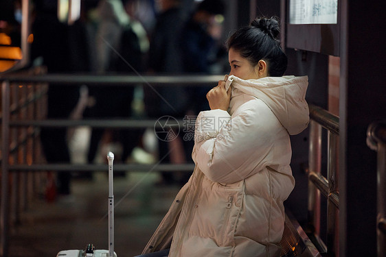 寒冬 美女夜间出行坐在站台等待公交车图片