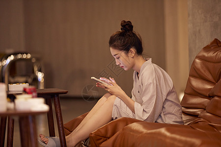 青年女性在汤泉馆休息区玩手机游戏图片