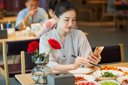 青年美女在汤泉馆美食区吃饭玩手机图片