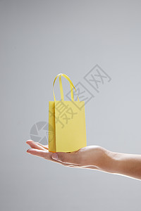 单手托着迷你购物纸袋特写图片素材