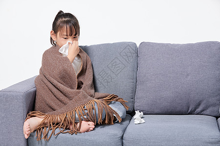 儿童感冒生病坐在沙发上擦鼻涕高清图片