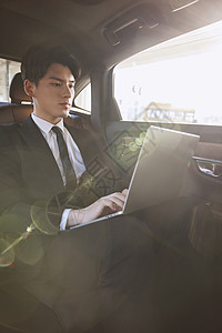 商务精英男士坐在轿车里办公图片