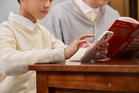 孩子在玩手机祖孙在书房看书玩手机特写背景