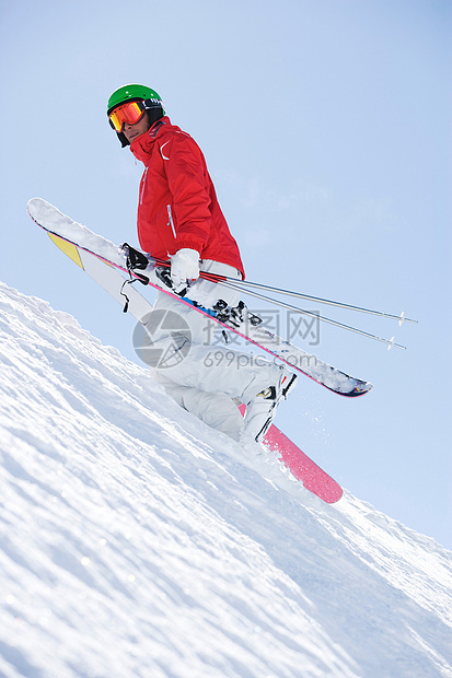 穿着红色滑雪服背着滑雪板上山图片