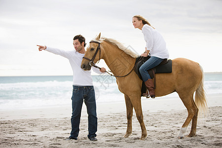 在海滩上骑马的情侣图片