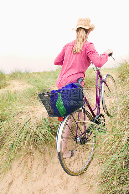 女人在海滩上推自行车图片
