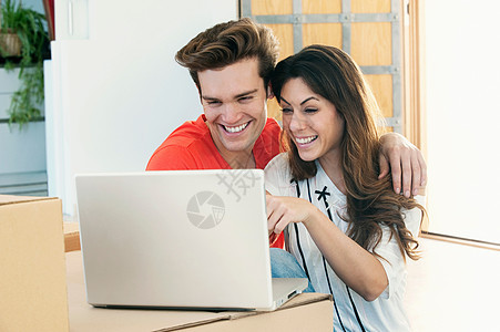 使用笔记本电脑一起微笑的情侣图片