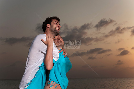 日落时在海滩拥抱的情侣图片