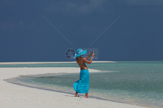 妇女在热带海滩拍照图片