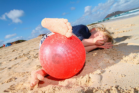 在海滩上玩红球的男孩图片
