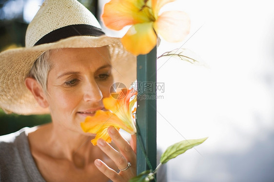 老年妇女在户外闻花香图片