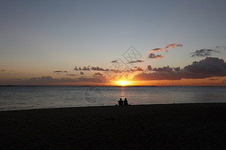 日落时坐在海滩的夫妇剪影图片
