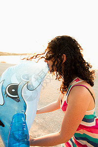 女人在海滩上亲吻充气海豚图片
