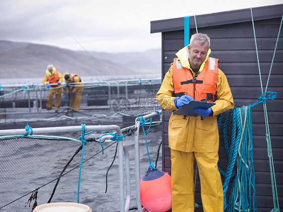 农民在苏格兰鲑鱼养殖场上做笔记图片