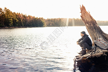 男人坐在山湖边的巨石上图片