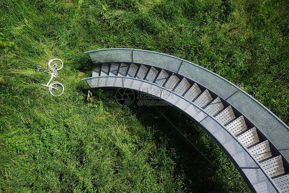 在螺旋楼梯下的草丛中自行车图片