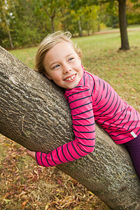 微笑的女孩在户外抱着树图片