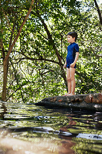 男孩站在森林中的河边图片