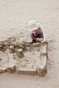 男孩在海滩上建沙堡图片