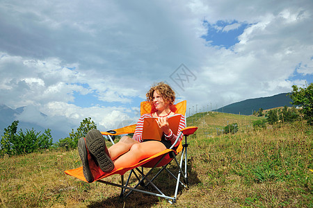 妇女在山坡上的草椅阅读图片