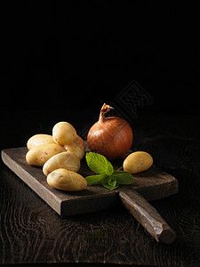 砧板上的土豆洋葱和薄荷叶图片