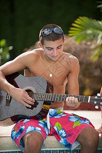 少年男孩在泳池边弹吉他图片