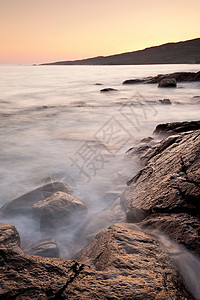 在岩石海滩上冲洗的波浪图片