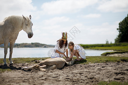 女孩在沙滩上与马玩耍图片