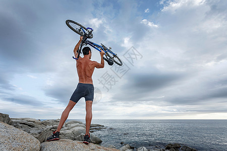 男子在巨石上举起自行车图片