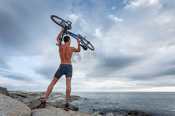 男子在巨石上举起自行车图片