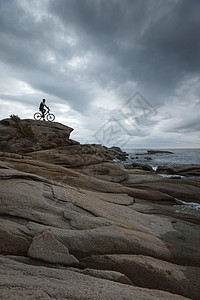 巨石上骑自行车的男人图片