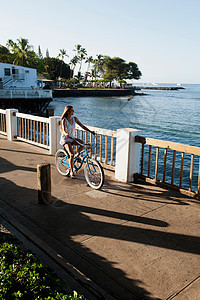 水边骑自行车的妇女图片