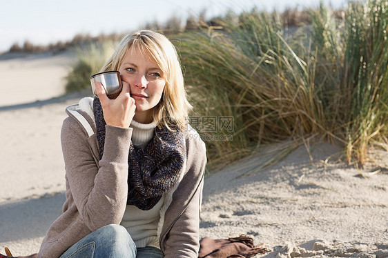 女人在海滩上喝热水图片