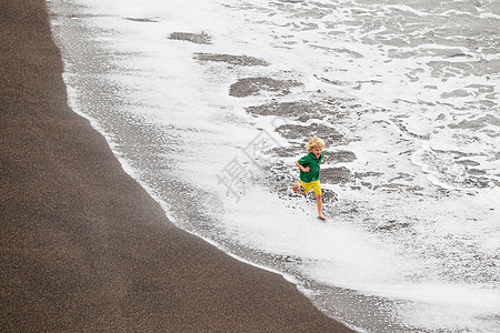 男孩在海滩上玩浪游戏图片