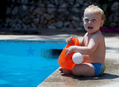 坐在游泳池旁边的婴儿男孩图片
